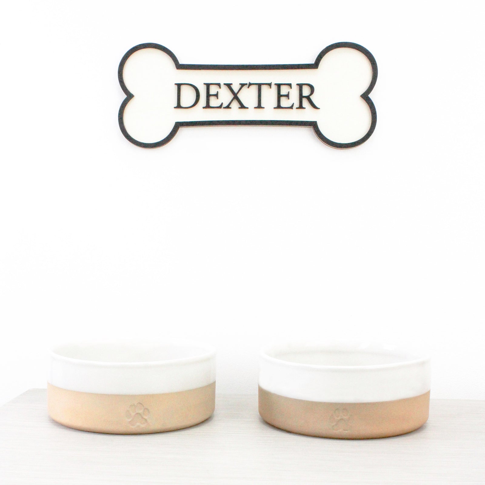 Personalised Dog's Name Wall Sign Shaped as a Bone, with Raised Wooden Wording in Black against wooden background, Pet Gift