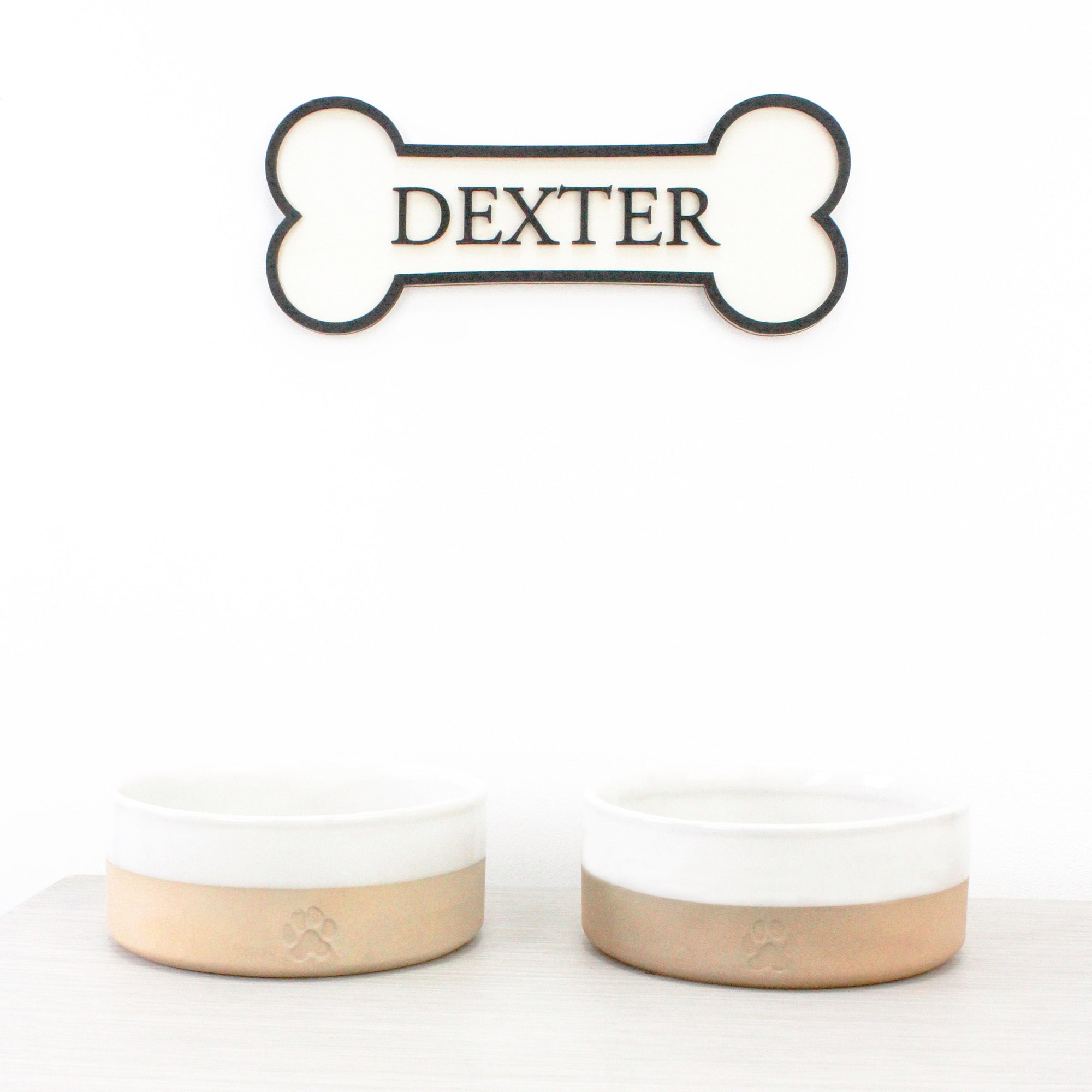 Personalised Dog's Name Wall Sign Shaped as a Bone, with Raised Wooden Wording in Black against wooden background, Pet Gift